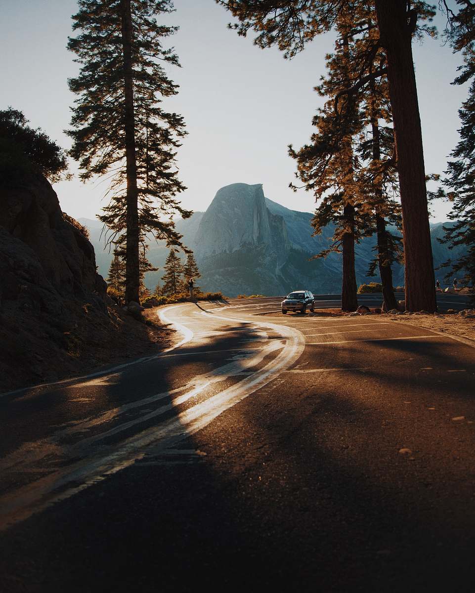 dirt road car on curve road surrounded by trees gravel